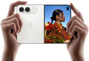 iPhone&nbsp;Duo, Star White colour, held by two hands in horizontal orientation, unfolded, left panel shows 48MP Dual Fusion rear cameras, right panel shows person getting their picture taken on outer display, the subject of the photo is able to see their face as their picture is getting taken using Duo Preview