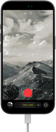 iPhone 18 Pro, front exterior, displaying a mountainous landscape, with the camera mode overlay in Time-Lapse mode, with power cord attached to charging port